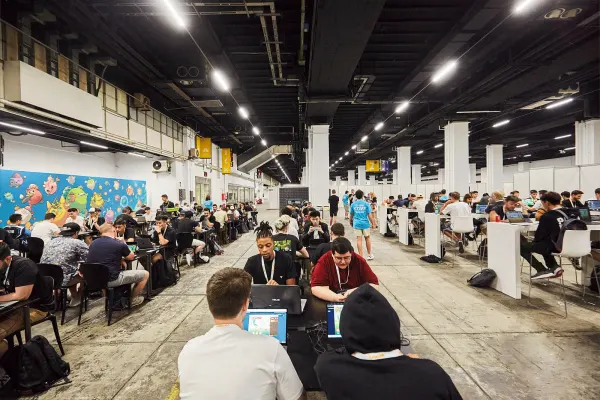 Jugadores con notebooks y tablets en el salón de la comunidad, con ilustraciones de Axie en las paredes